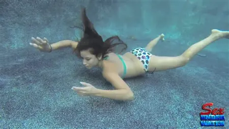 تحاول فتاة رفيعة أن تمتص ديك مطاطي تحت الماء